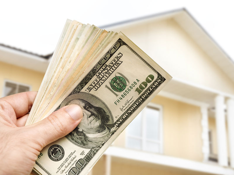 holding money in front of a house